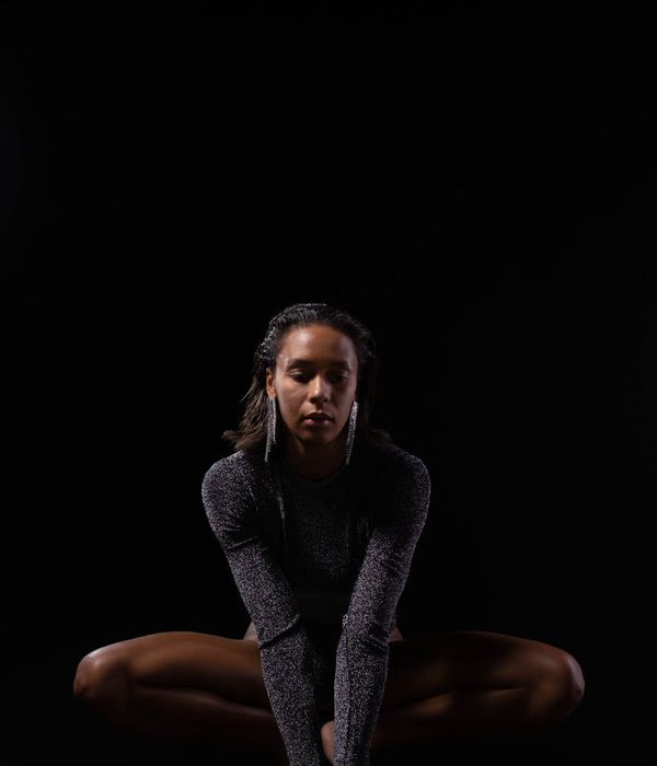 Woman in a calm yoga pose against a dark, serene background.